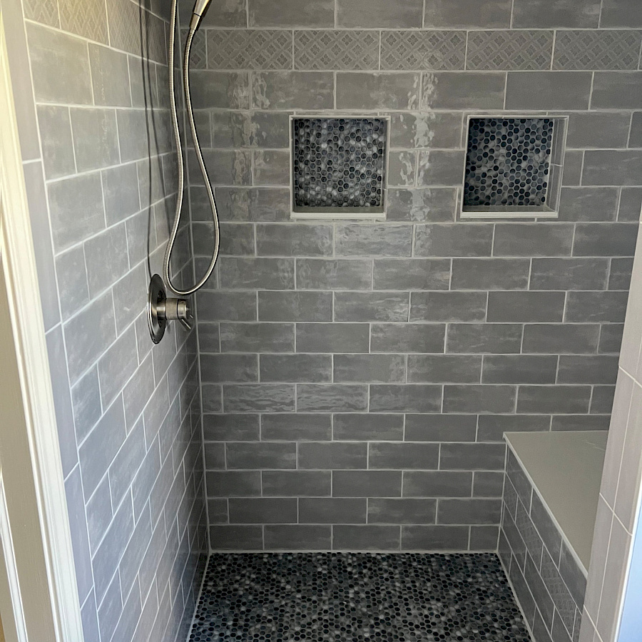 Custom tiled shower with recessed niches in a bathroom remodel by Sparrow Contracting
