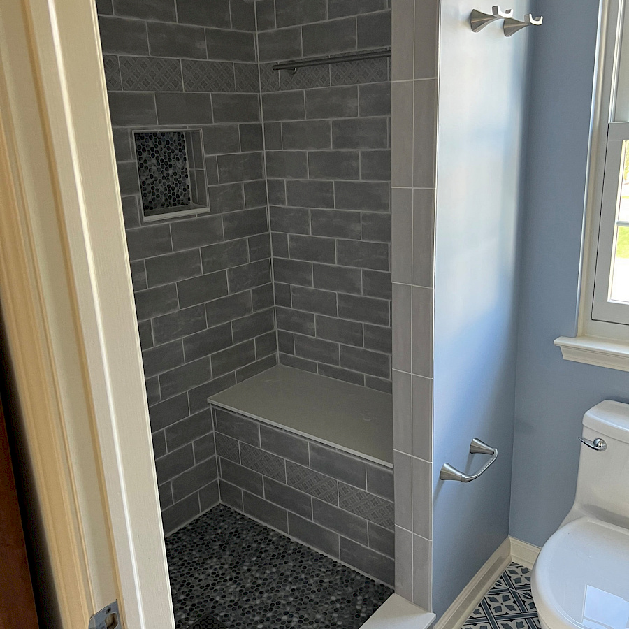 Walk-in tile shower with a built-in bench in a bathroom remodel by Sparrow Contracting