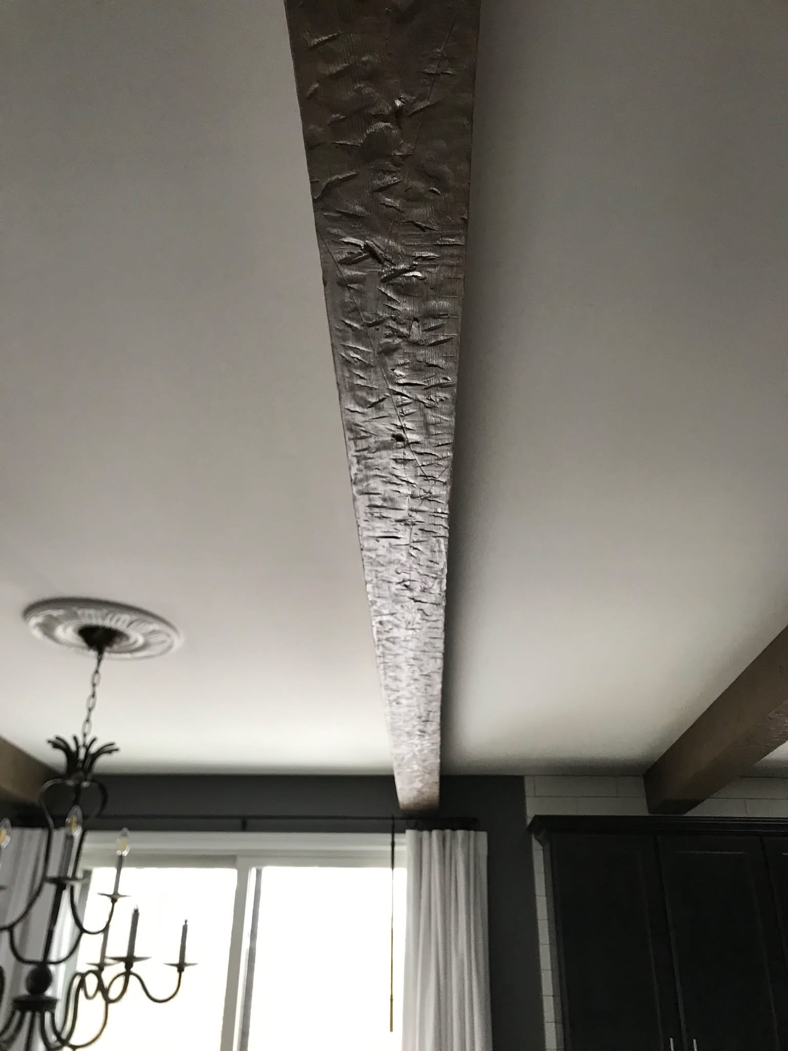 Hand-hewn barn beam installation as a ceiling accent